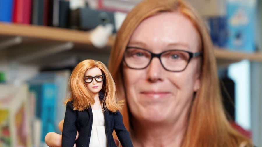 COVID-19 vaccine developer Sarah Gilbert holds up Mattel's newest Barbie doll, made in her likeness to honor her work during the pandemic. 