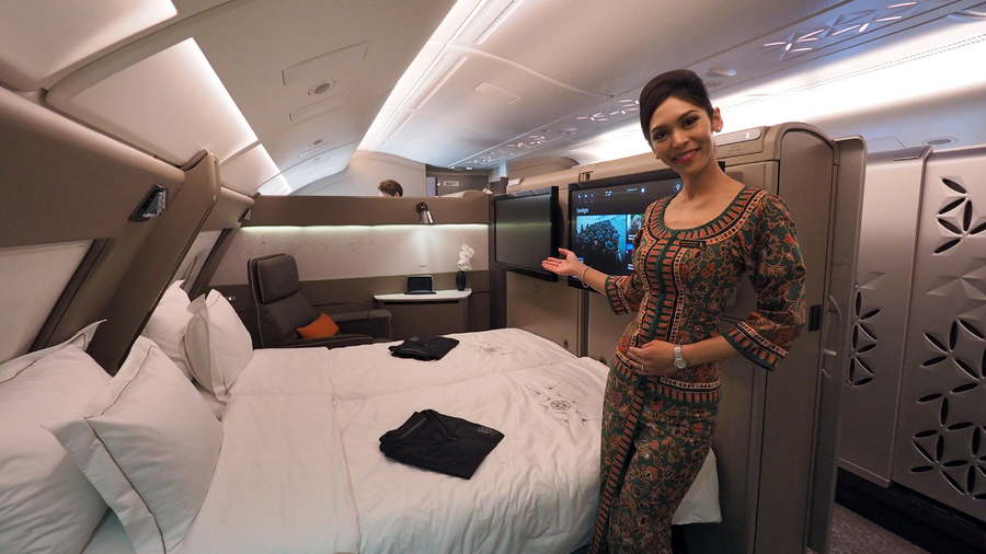Flight attendant showcases Singapore Airlines' luxurious first-class suites, complete with two full-length beds and TVs.