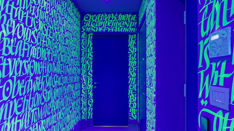 Vibrant Defhouse hallway covered in glow-in-the-dark handwriting.