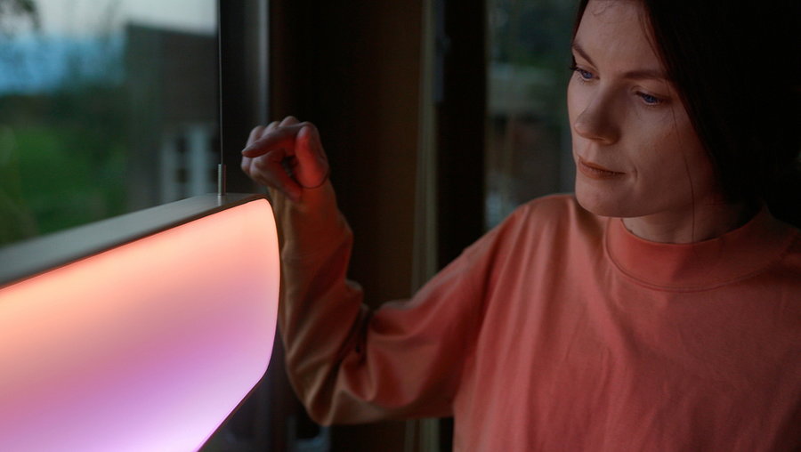 Woman changes the settings of her Sunne solar light using its built-in touch controls.
