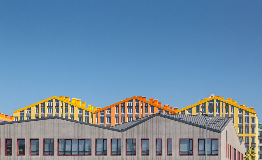 Gabled orange and yellow rooftops of the Comfort Town development peek out over a shared central structure. 