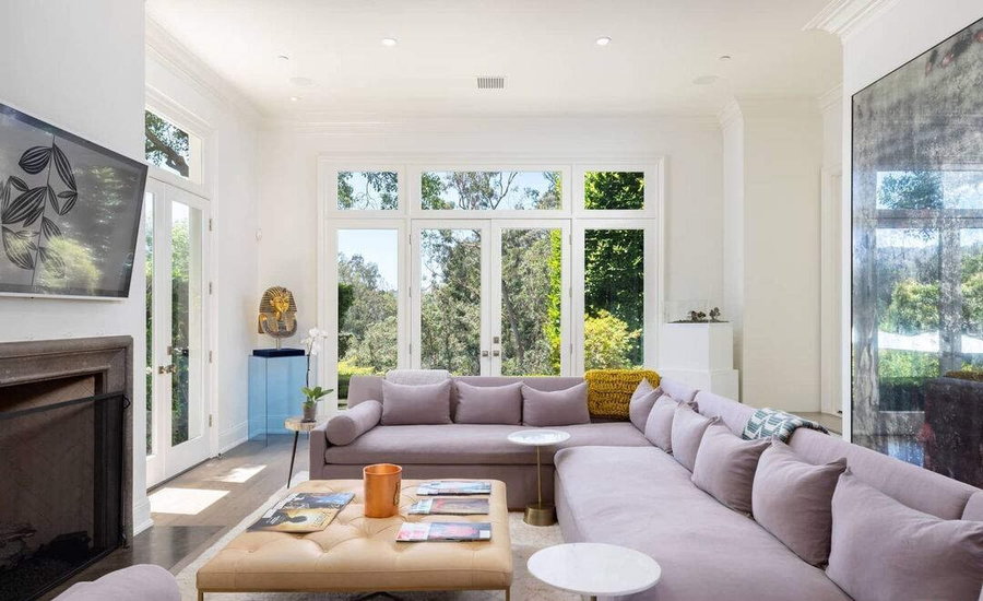 Simple, open living room in Katy Perry's on-sale Beverly Hills mansion, complete with a calming lilac couch.  