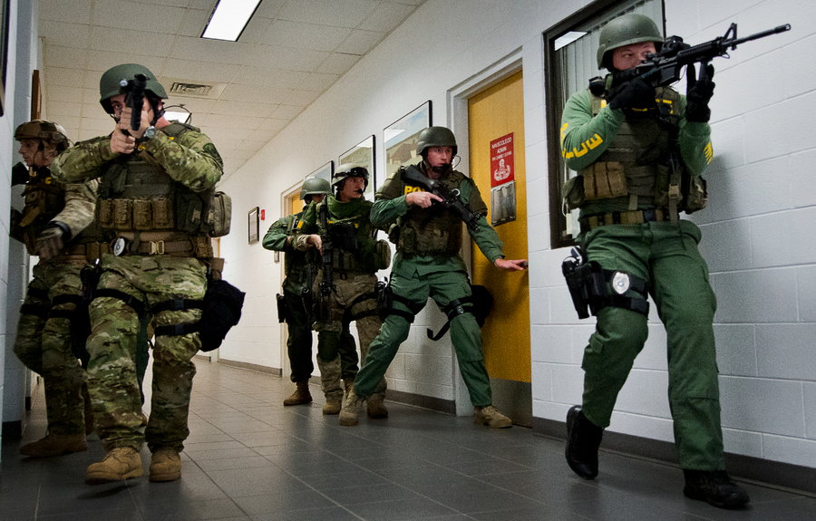 Military personnel move through a school to protect students during a mass shooting