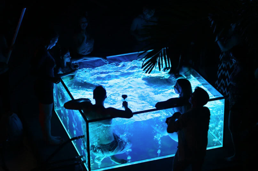 Group of friends enjoys a fun night in the futuristic Nautilus all-glass hot tub.