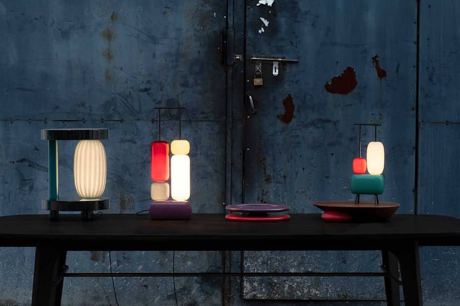 Pieces from Stellar Works' sculptural Space Invaders lamp collection light up a small dark table. 