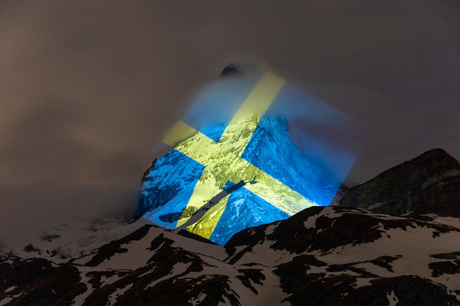 The bold blue and yellow of the Swedish flag pop against the mountain's black and white face. 