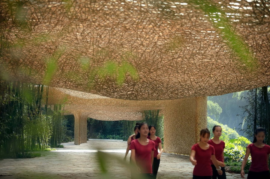 A group of theater-goers walks beneath the shelter of the bamboo canopy. 