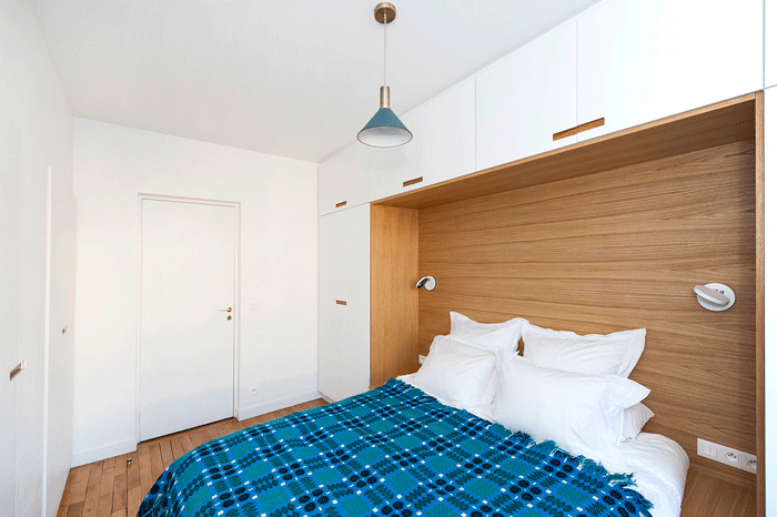 The bedroom of a Clichy apartment renovated by Atelier Pierre Louis Gerlier, complete with built-in storage and a wooden nook for the bed.