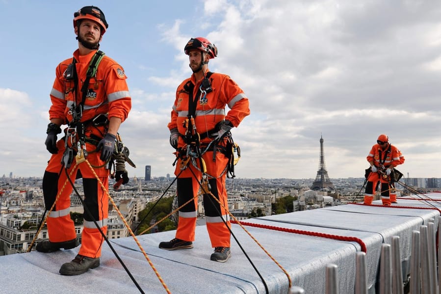 Workers on top of the Arc de Triomphe roll down ropes and fabric to bring Christo's surreal vision to life.