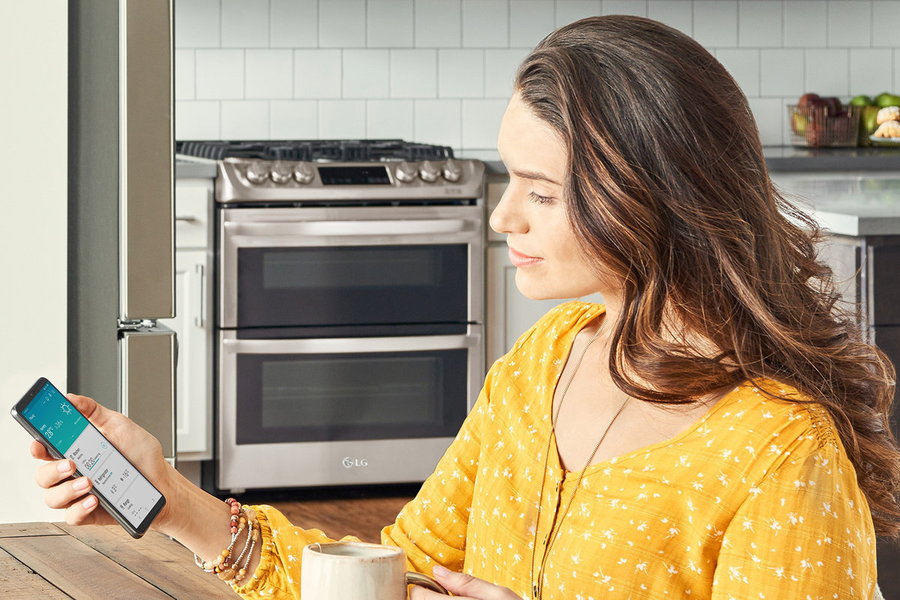 Woman uses the LG ThinQ App to wirelessly preheat her oven.