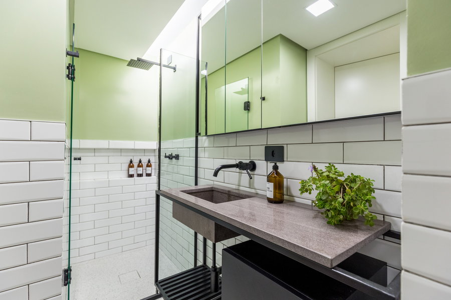Pristine white tiles, mint green paint, and lots of mirror's make up this micro-apartment's bathroom.