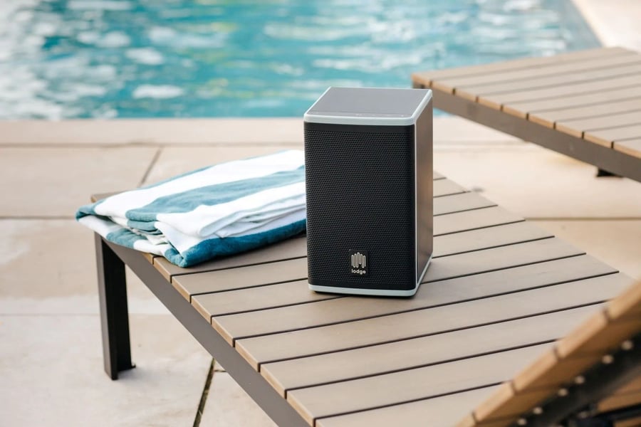 Lodge Solar Powered Speaker sits on table near the pool.
