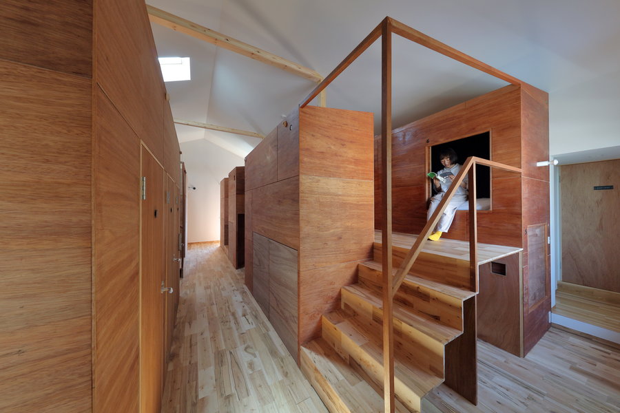 Young girl steps out of her capsule in Alphaville Architects' new  Kyoto Suiden-ann Hostel.