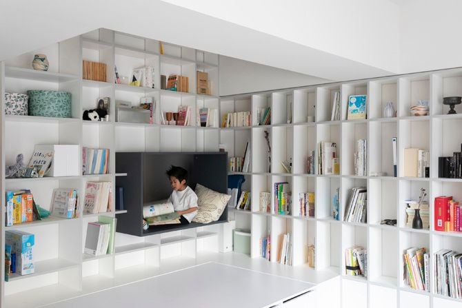 Child cozies up with a book in a small play space built into the 