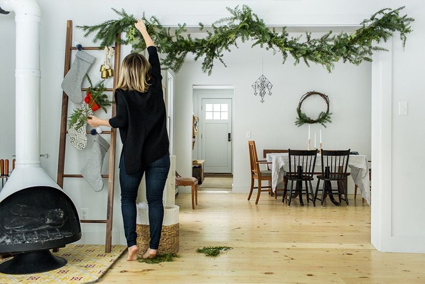 Woman hangs up twigs and garland she found outside her home for cozy, cost-effective holiday decorations.