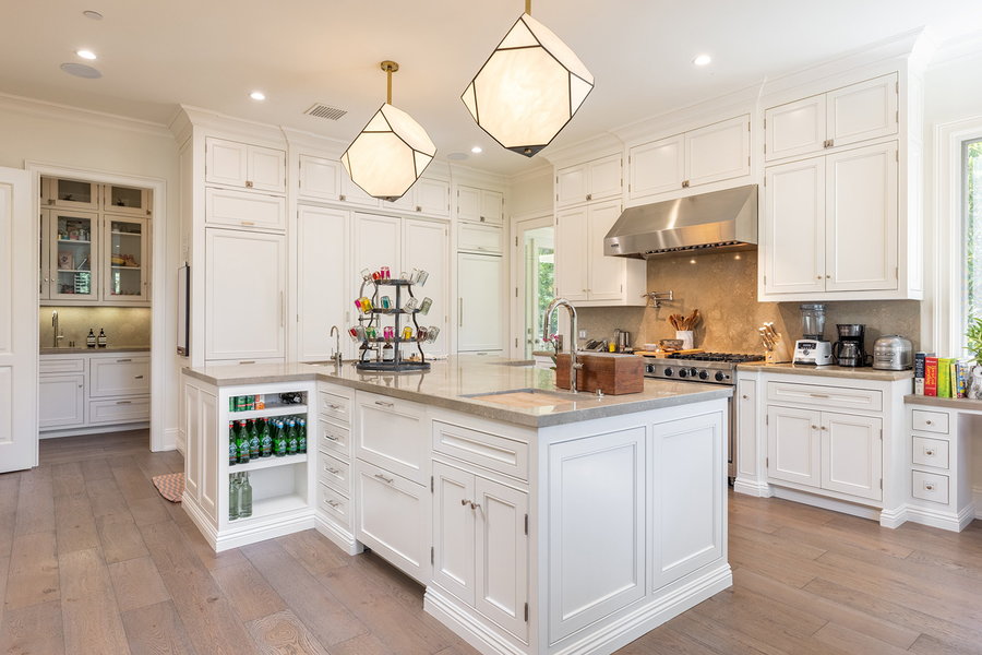 Expansive white kitchen space in Katy Perry's on-sale Beverly Hills mansion, complete with trendy geometric pendant lights.