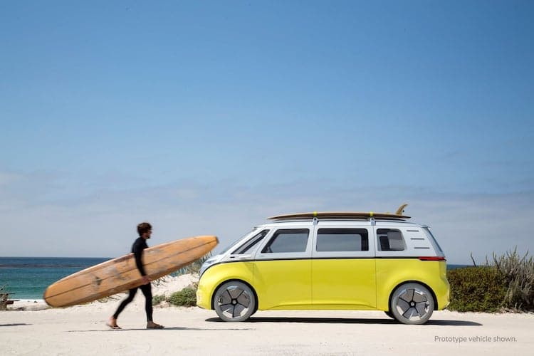 Surfer runs to put his board back on the roof of his fully electric Volkswagen I.D. Buzz.