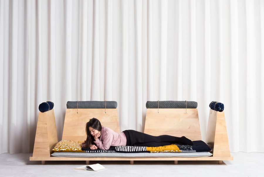 A young woman enjoys a good book while laying down across the base of her Zabuton sofa. 