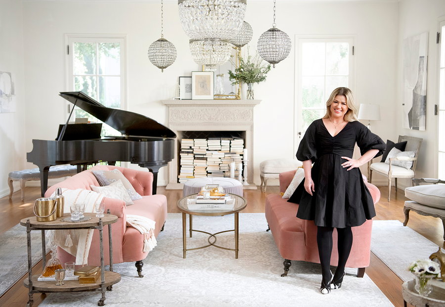 Singer Kelly Clarkson stands in front of her soft, airy furniture pieces made in collaboration with Wayfair. 