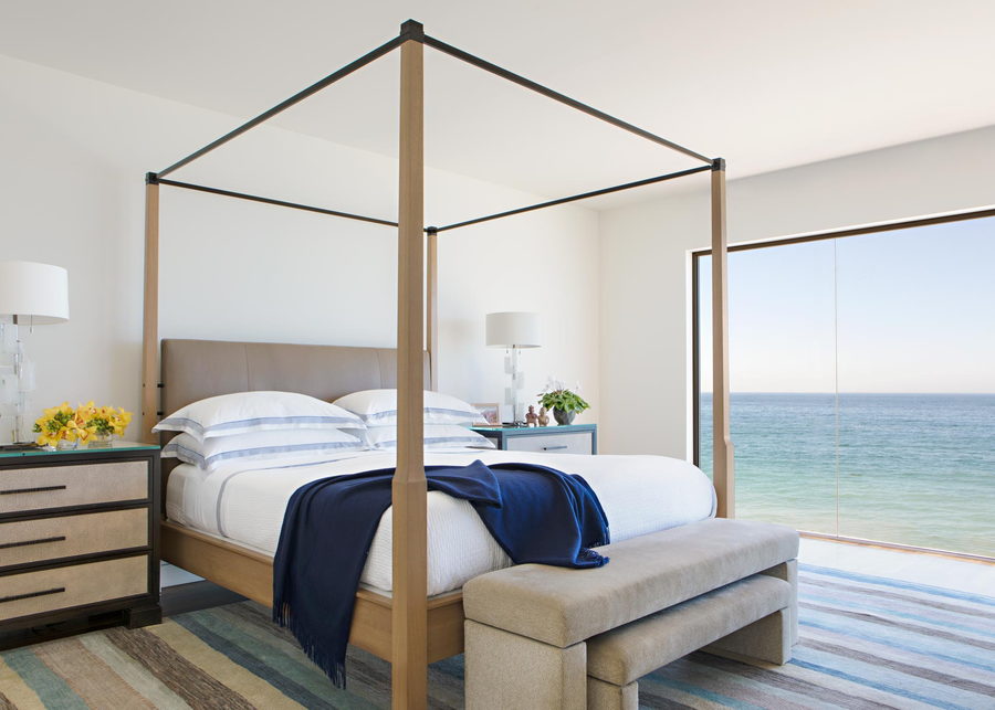 The minimalist white master bedroom inside the metallic Malibu beach house.