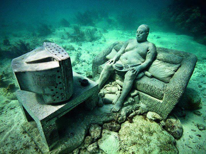 Underwater sculpture at MUSA depicts a man sitting on the couch watching TV.