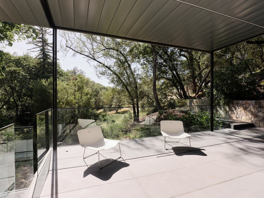 Two white chairs sit on a balcony space in the Suspension House, enjoying gorgeous views of the surrounding nature.