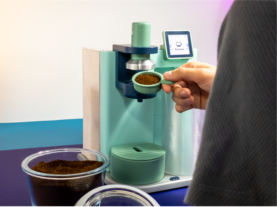 User loads coffee grounds into their recyclable, repairable Kara coffee machine.