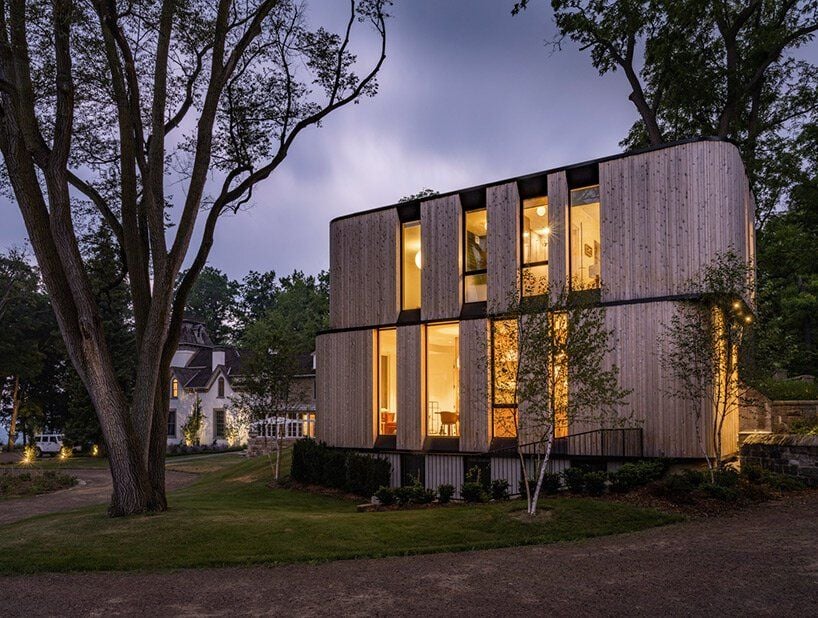 Side view of the glowing Fold House in the falling dusk. 