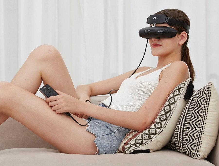 Young woman enjoys her favorite movies through her GOOVIS Young VR headset. 