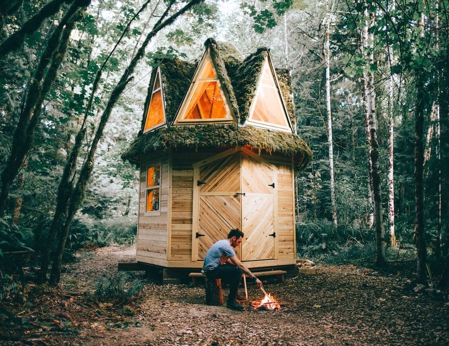 Jacob Witzling tends a fire in front of a small cabin on his 