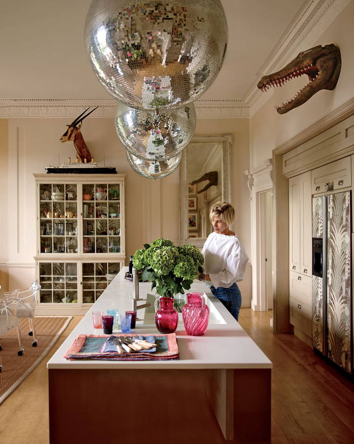 Woman tends to plants in a kitchen decked out in hanging disco ball fixtures.