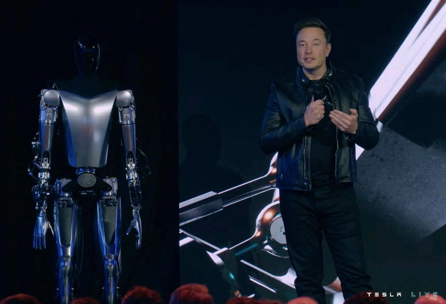 Elon Musk stands next to the latest Optimus robot prototype at Tesla AI Day 2022. 