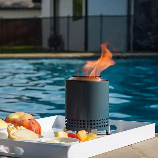 Mesa Tabletop Fire Pit rests on a white tray by the pool.