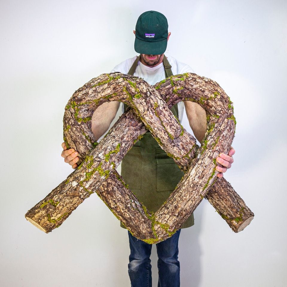 Christophe Guinet (aka Monsieur Plant) holds up his twisted heart-shaped tree trunk sculpture.