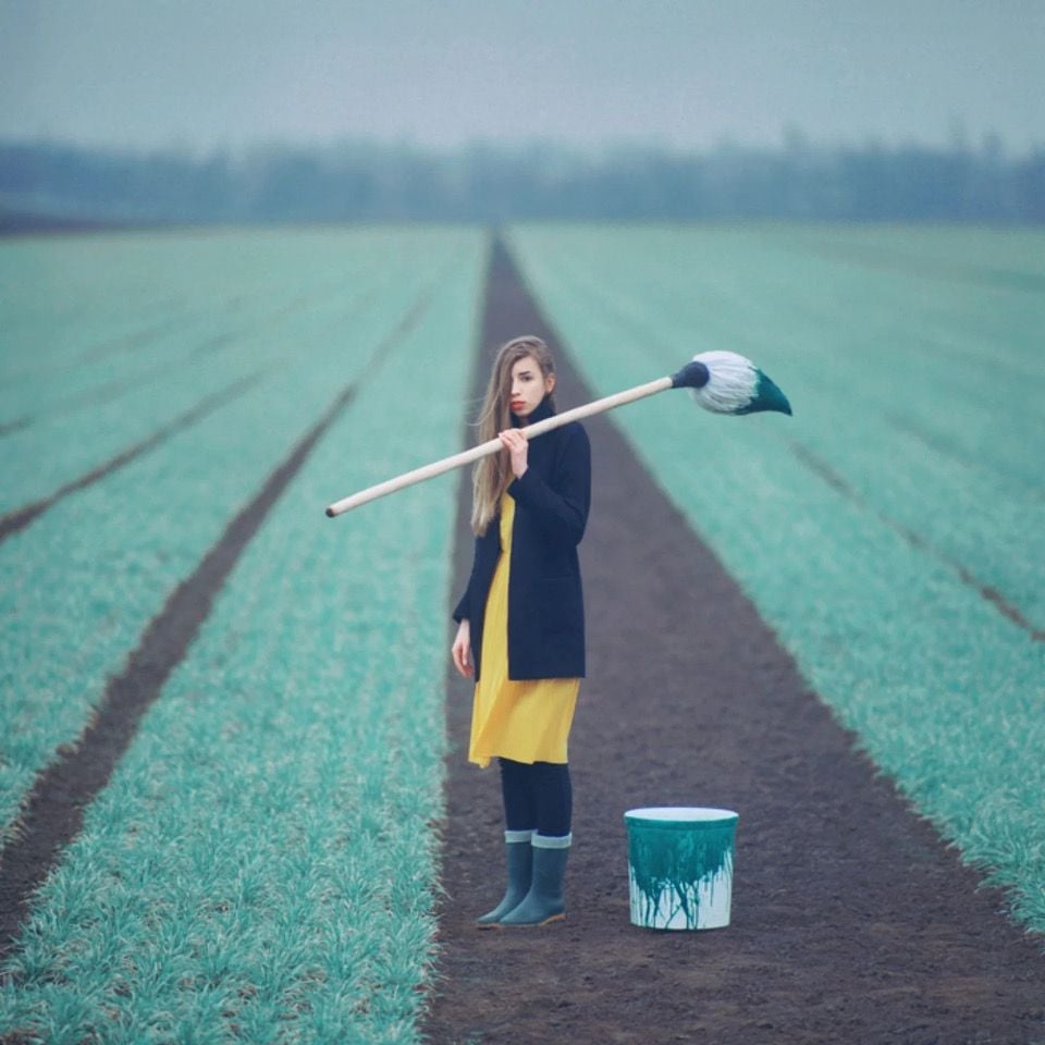 Surreal photograph by Ukrainian artist Oleg Oprisco shows a woman holding a giant paintbrush in the middle of a field. 