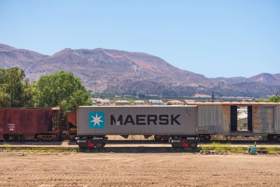 Parallel Systems' electric freight train modules transport a Maersk shipping container along a track.