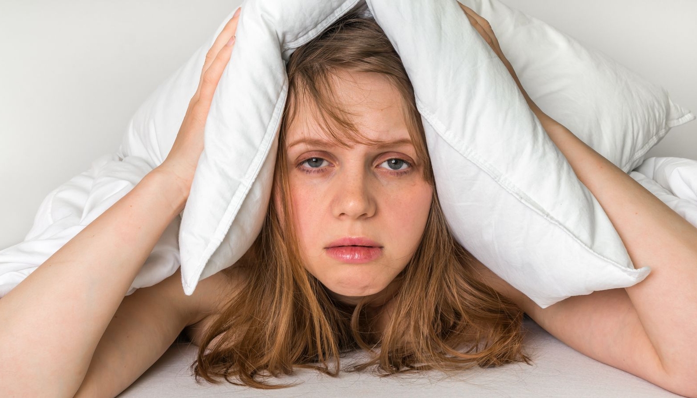 woman covering ears with pillow