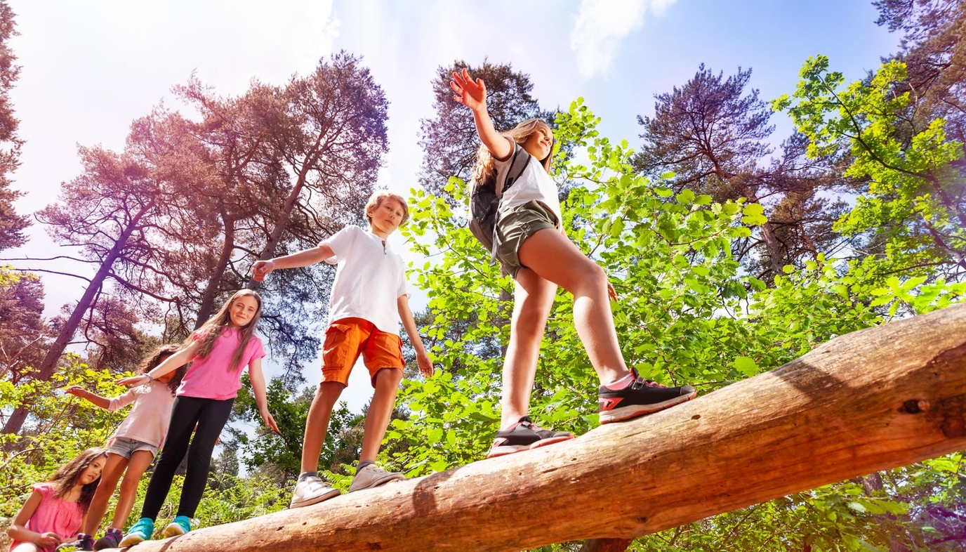 kids at summer camp walking over big log