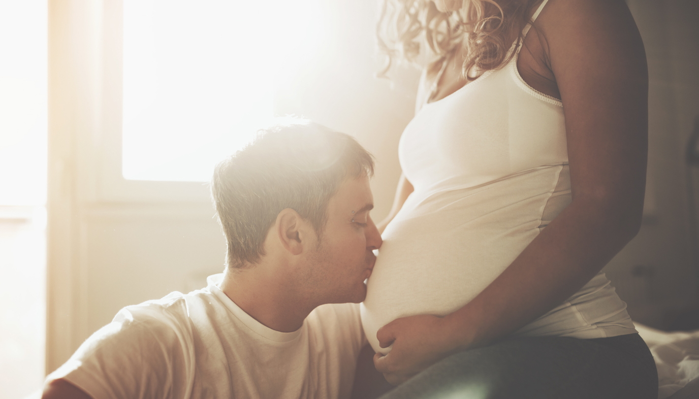 man kissing pregnant woman's belly