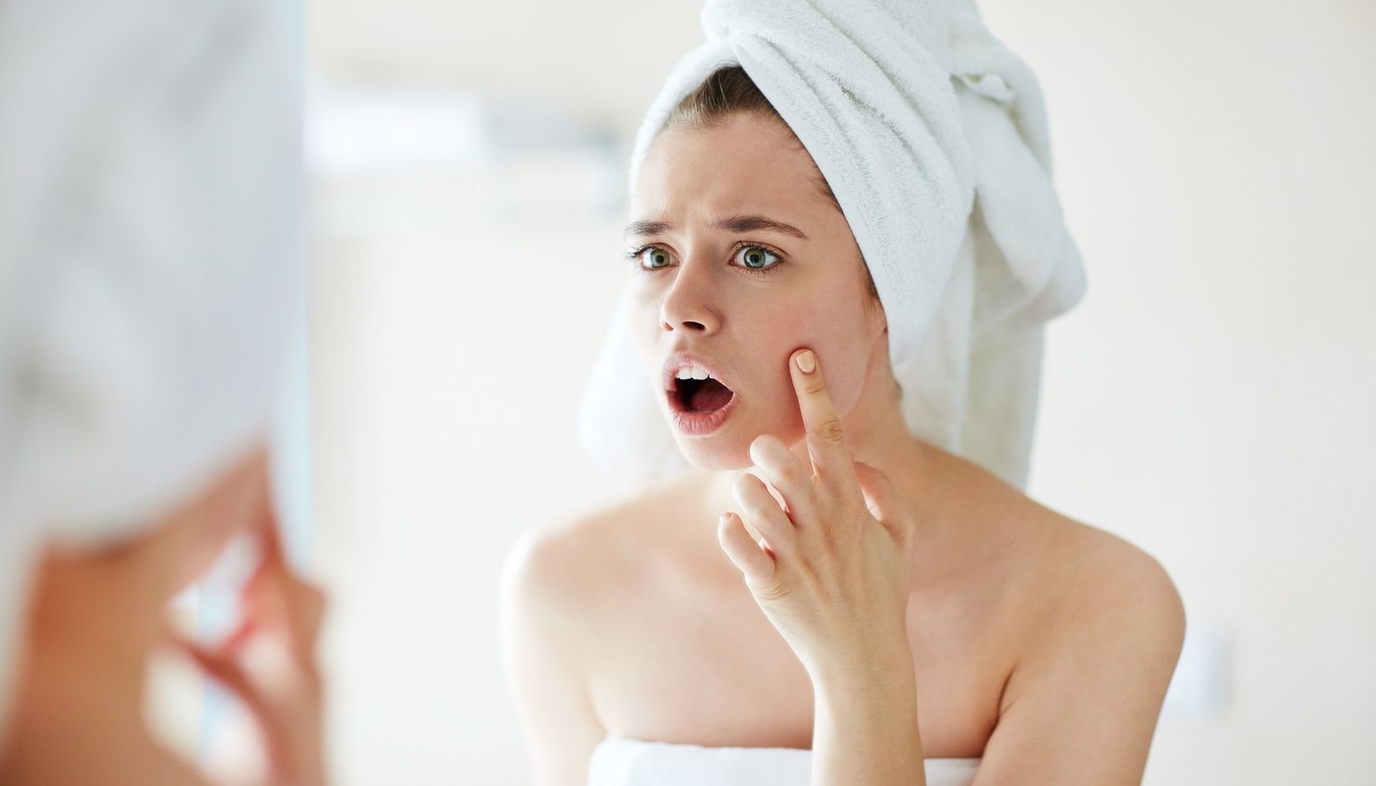 woman checking out pimple in the mirror