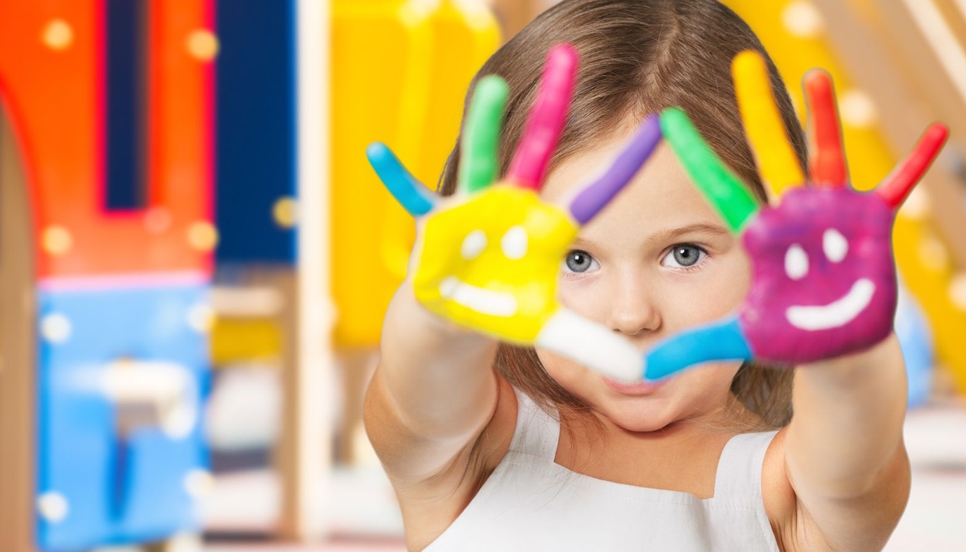 child at preschool with finger paint on her hands