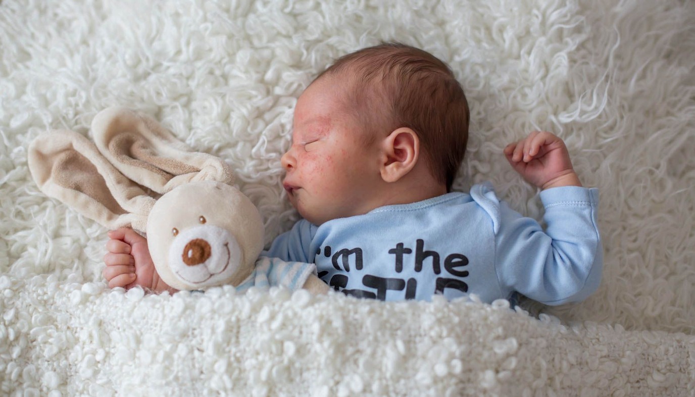 sleeping baby inside white blanket with teddy bear