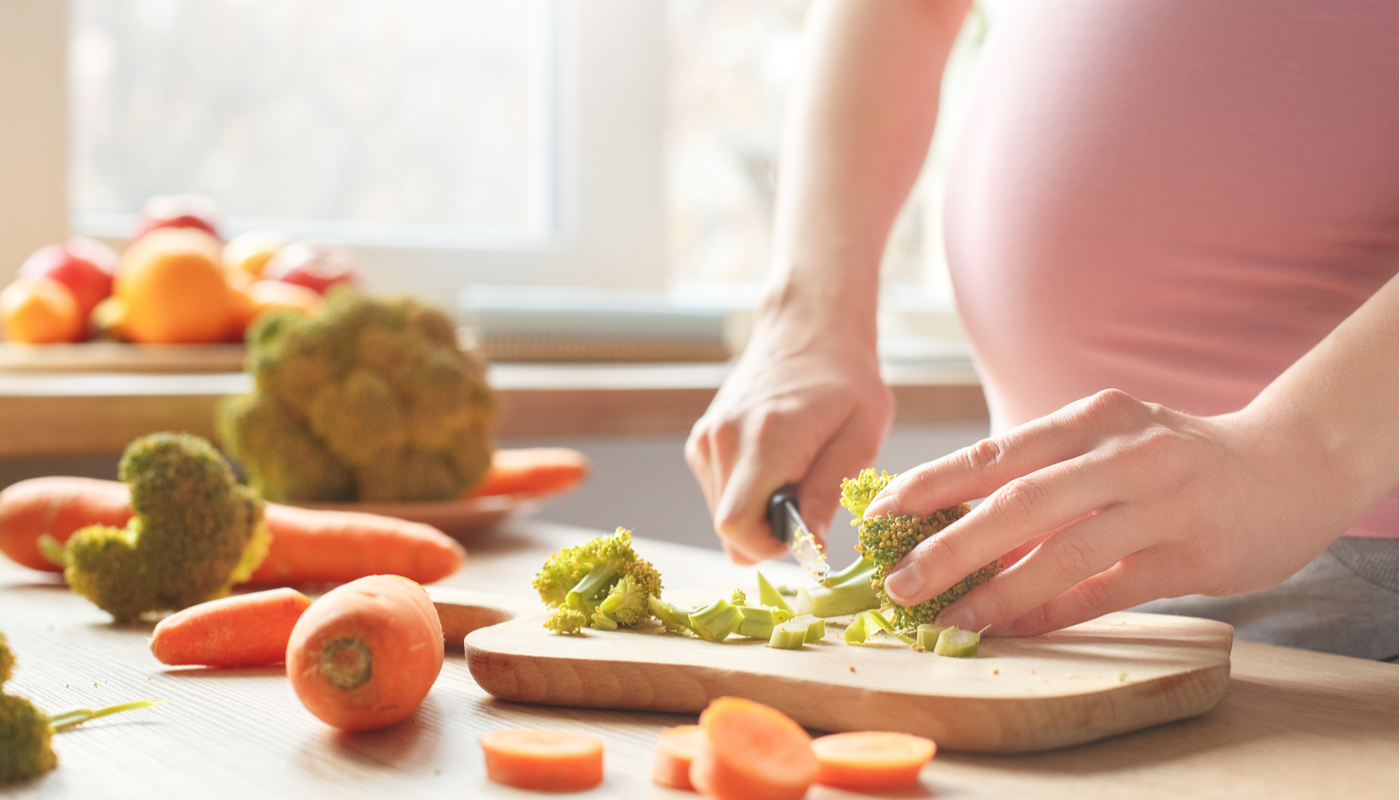pregnant woman cutting up vegetables