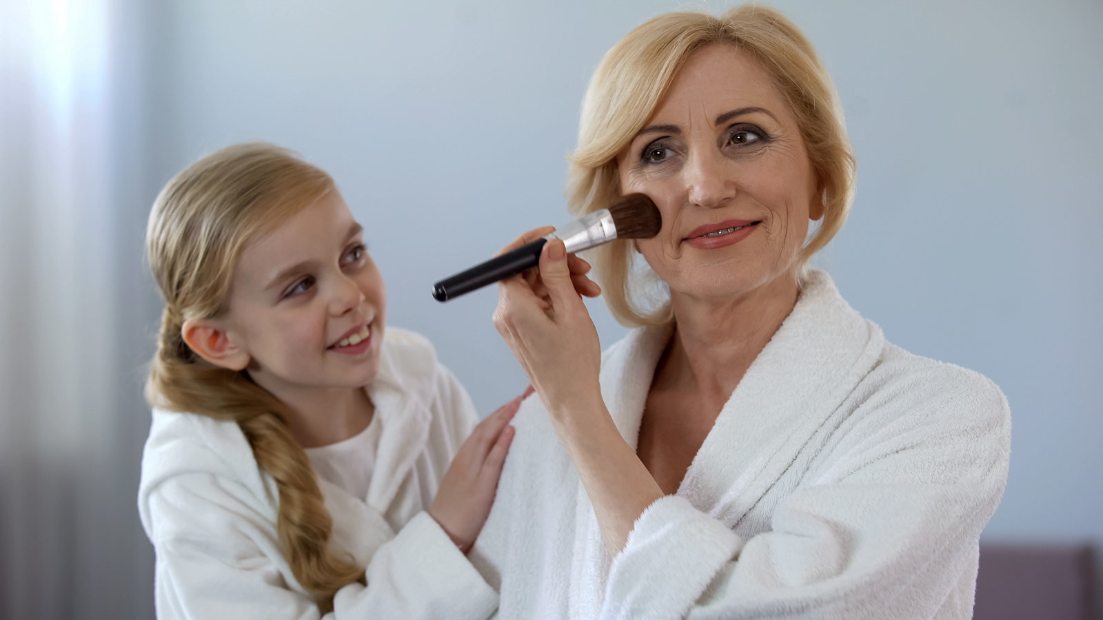 grandchild watching grandmother put on makeup
