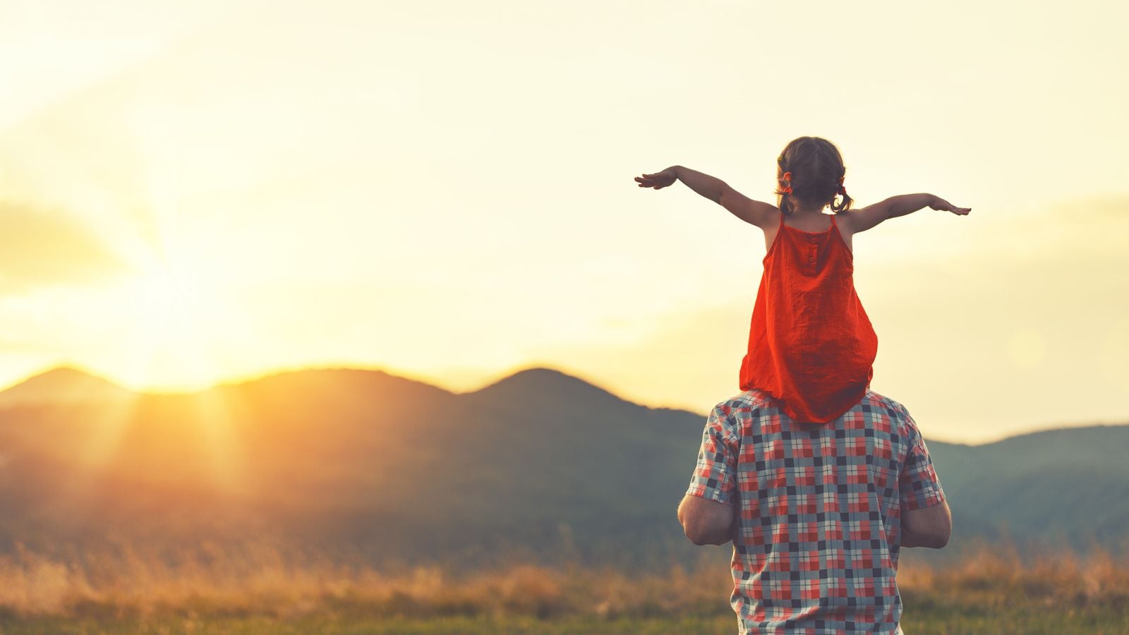 father carrying daughter on shoulders