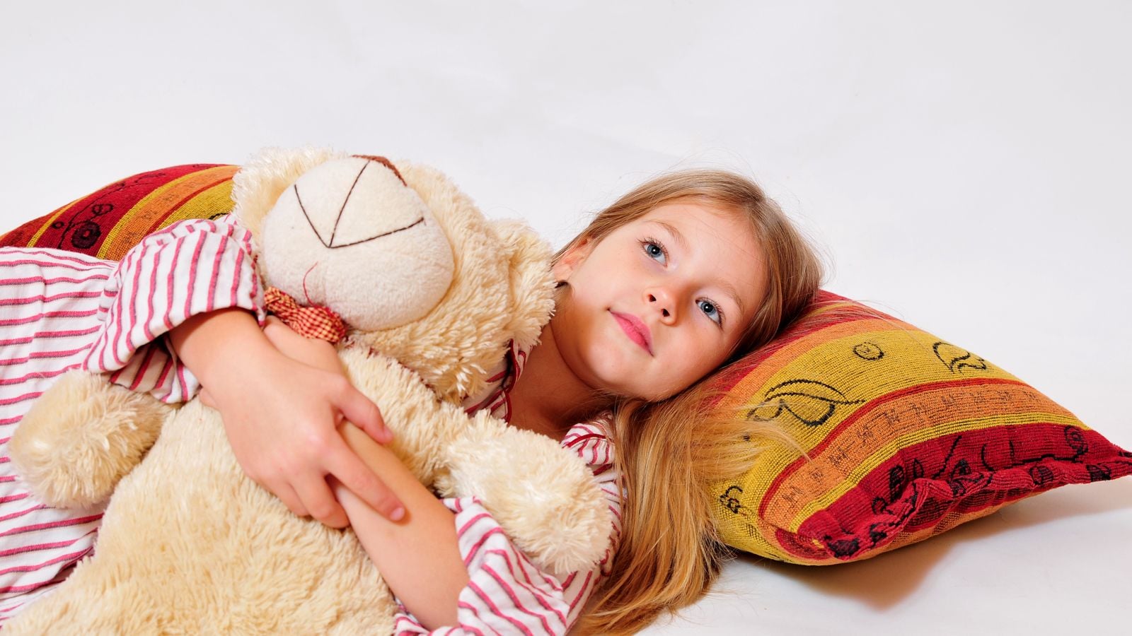girl lsleeping on pillow holding a teddy bear