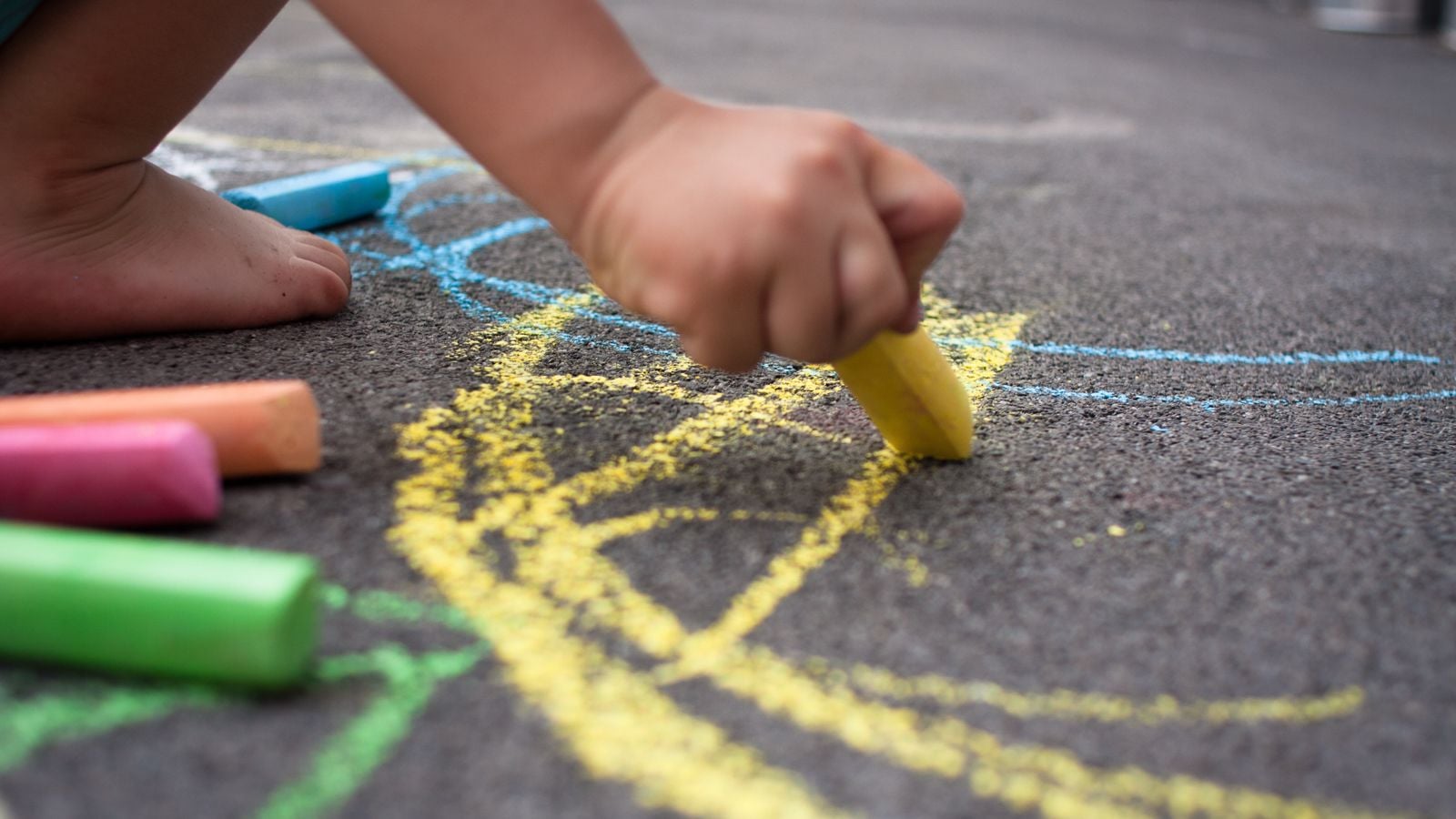 kid drawing on pavement with chalk