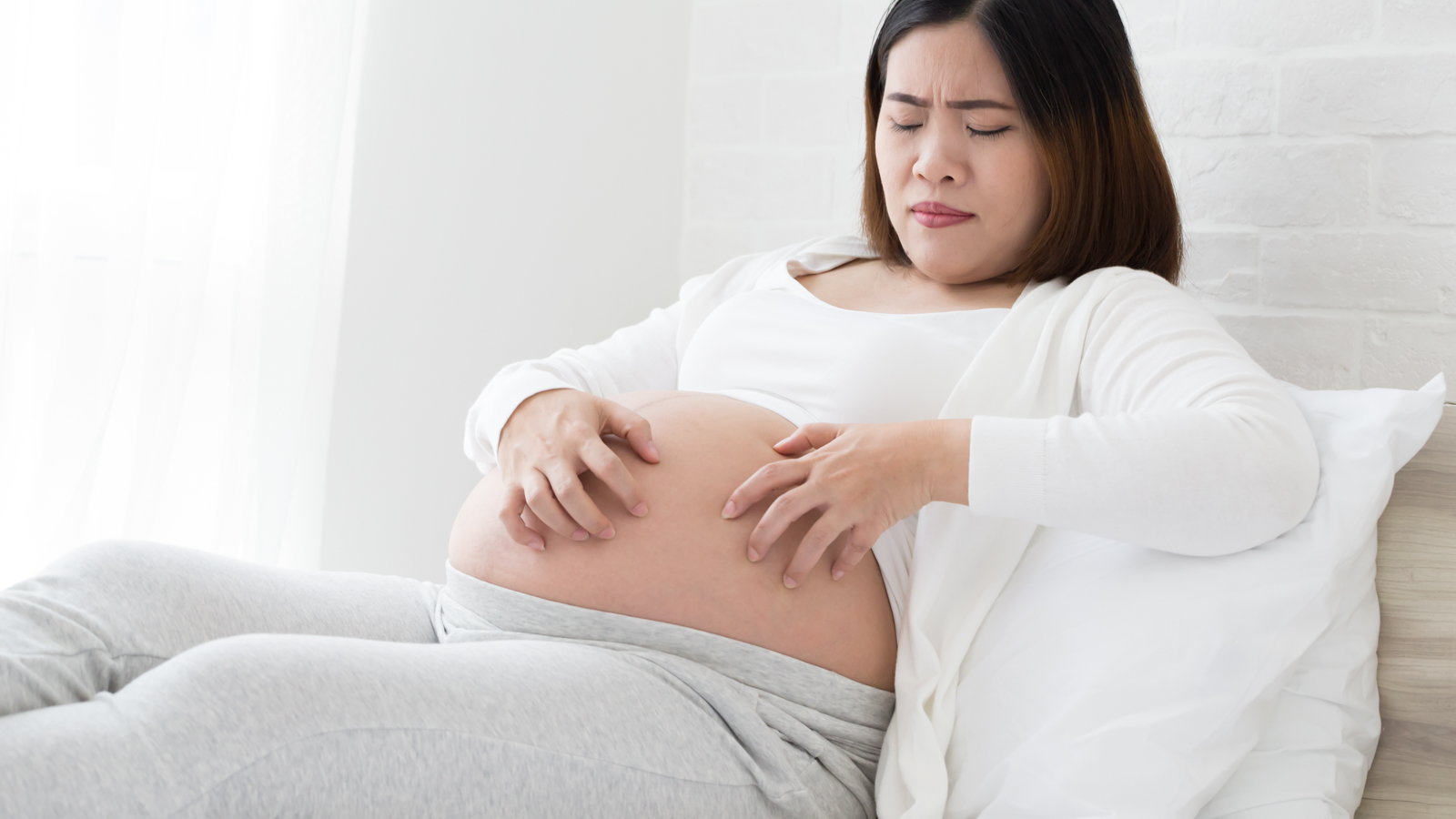 pregnant woman scratching stomach