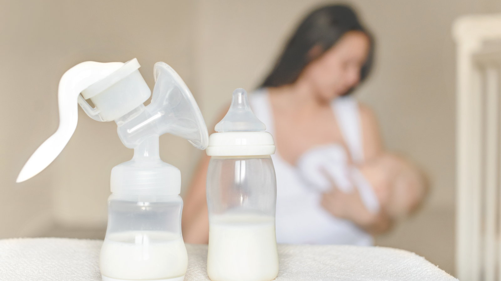 pumped breast milk with mother breastfeeding in background