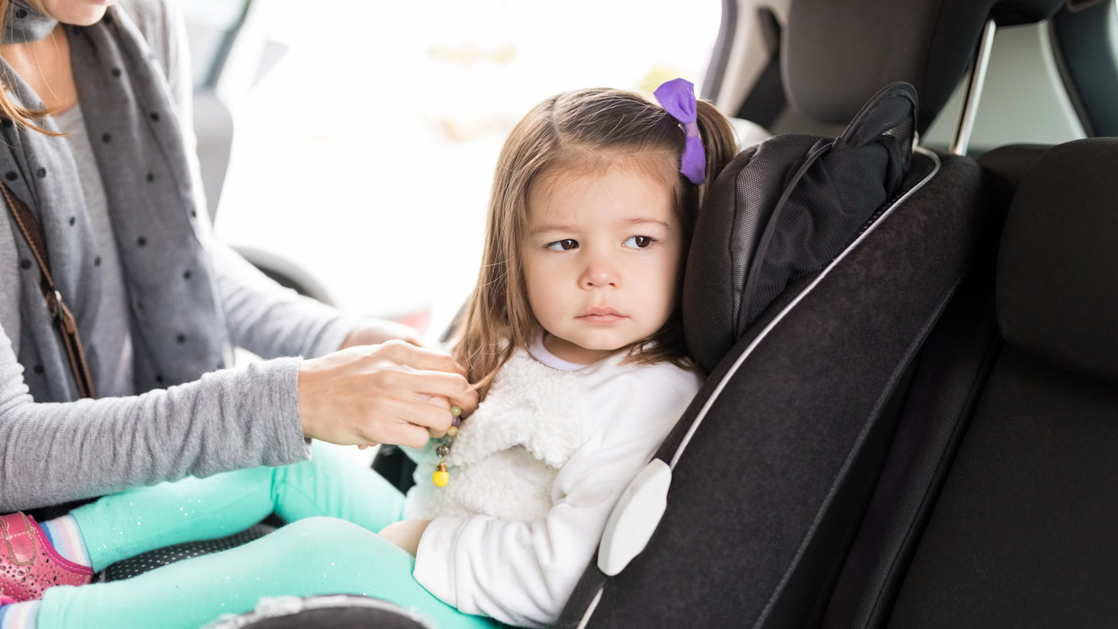 mom buckling toddler in carseat